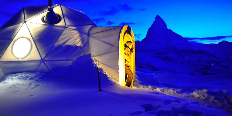 Cluster of packed snow domes on a mountain shelf under overcast winter light